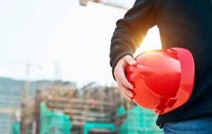 A man carries a red hardhat.